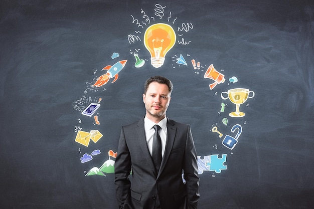 Presentation and seminar concept Portrait of handsome european businessman standing on chalkboard wall background with creative busines sketch