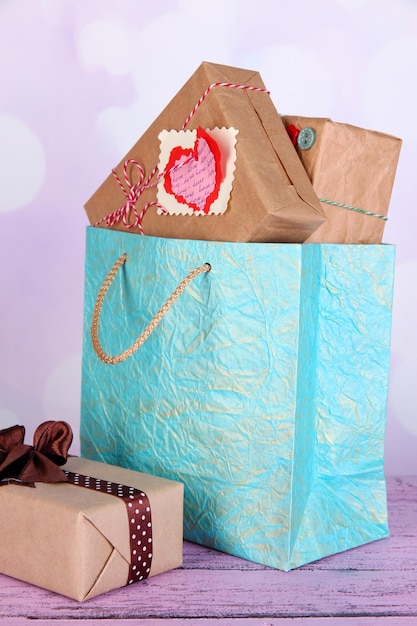 Presents in paper bag on table on bright background