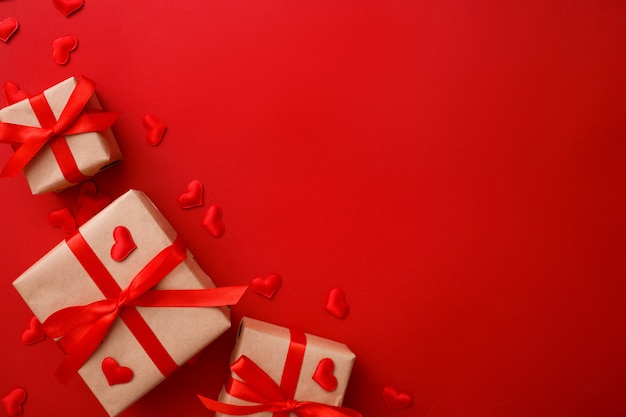 Presents with red bow on red  with heart confetti. Flat lay style. Valentine day 