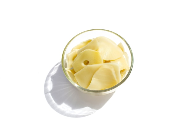 Preserved bamboo shoot slices in glass bowl on white background.