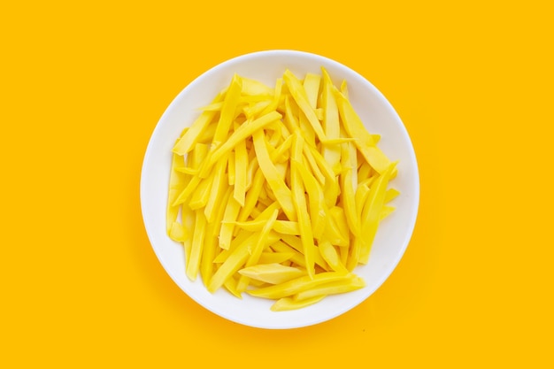 Preserved bamboo shoot in white plate on yellow background.