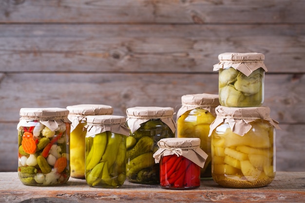 Preserved and fermented food. Assortment of homemade jars with variety of pickled and marinated vegetables on a wooden table. Housekeeping, home economics, harvest preservation