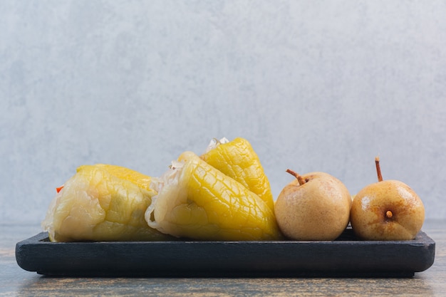 Preserved pepper and apple on a wooden plate , on the marble.