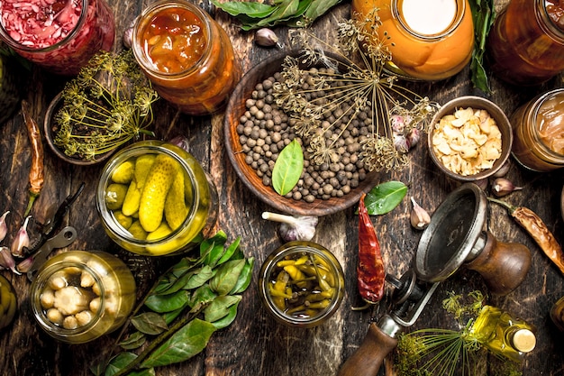 Preserved vegetables in glass jars with seamer. On a wooden table.