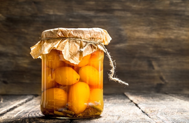 Preserves tomatoes in glass jar  on wooden table.