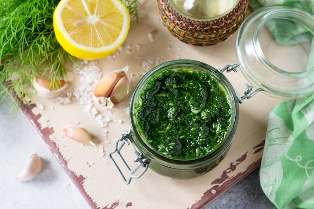 preserving dill with garlic and olive oil on the kitchen wooden table