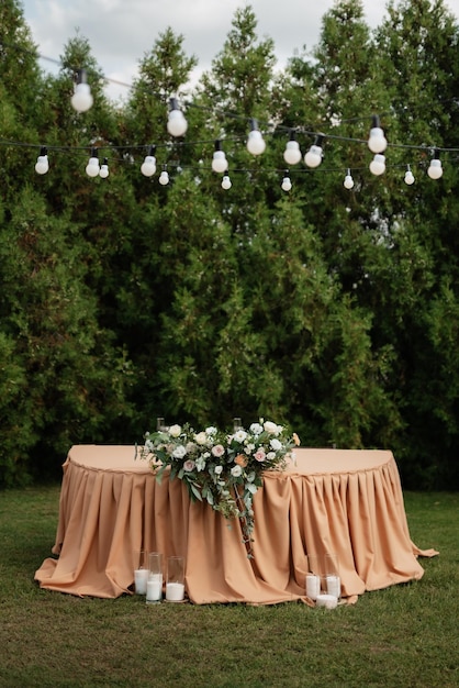 The presidium of the newlyweds in the banquet hall of the restaurant is decorated with candles and green plants wisteria hangs from the ceiling