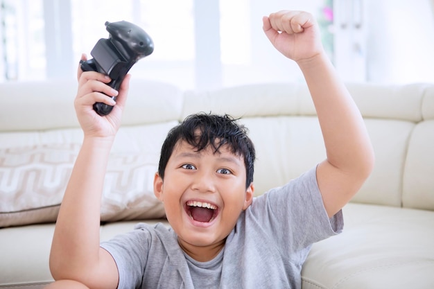 Preteen boy celebrating win while playing video game