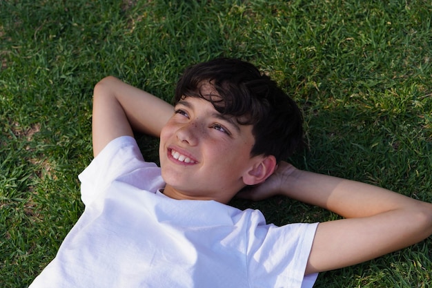 preteen boy with smiling freckles lying in shade