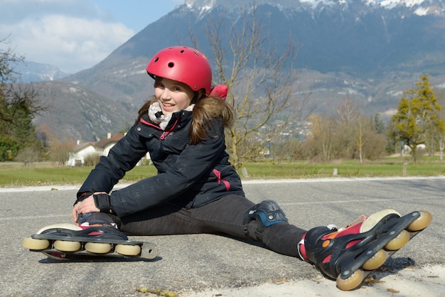 preteen girl in rollerskate sitting on the road