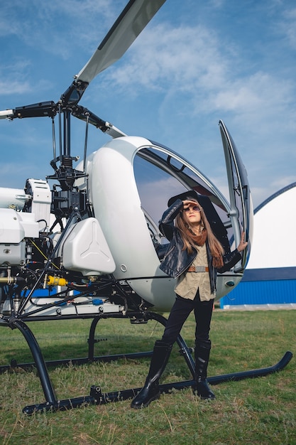 Preteen girl in sunglasses looking at sky near helicopter