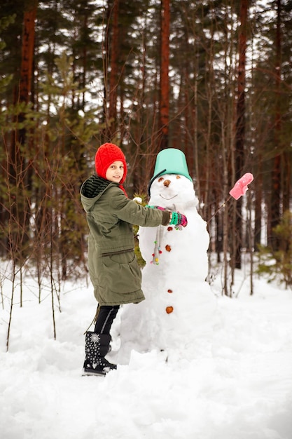 Preteen girl in winter to sculpt a snowman