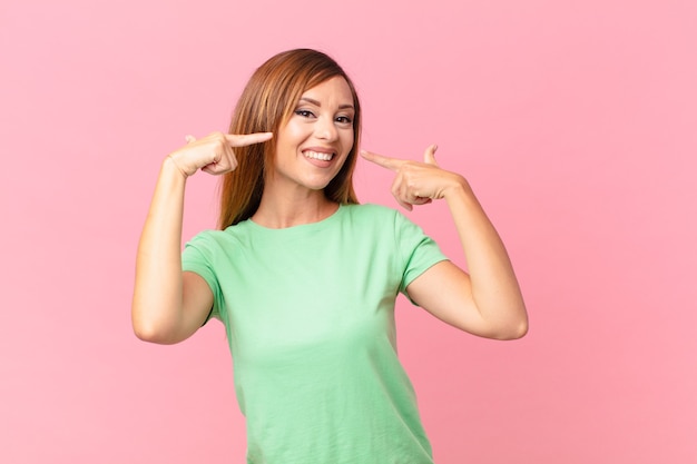 Pretty adult woman smiling confidently pointing to own broad smile