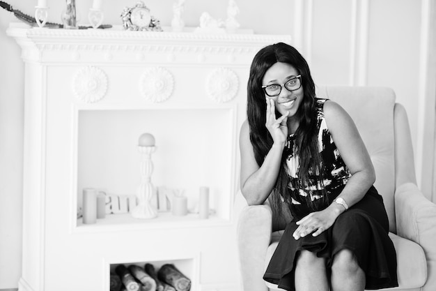 Pretty african american woman in eyeglasses posed in room sitting on yellow chair