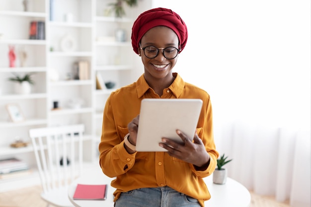 Pretty african american woman posing at office holding digital tablet