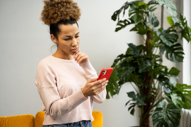 A pretty african young woman uses a smartphone smiles looks at the screen reads sms messages