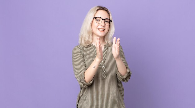 Photo pretty albino woman feeling happy and successful smiling and clapping hands saying congratulations with an applause