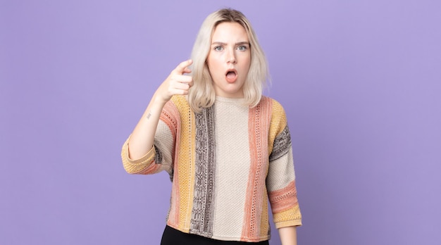 Pretty albino woman pointing at camera with an angry aggressive expression looking like a furious, crazy boss