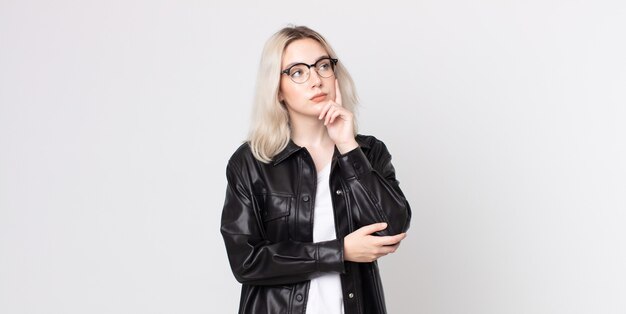 Pretty albino woman with a concentrated look, wondering with a doubtful expression, looking up and to the side