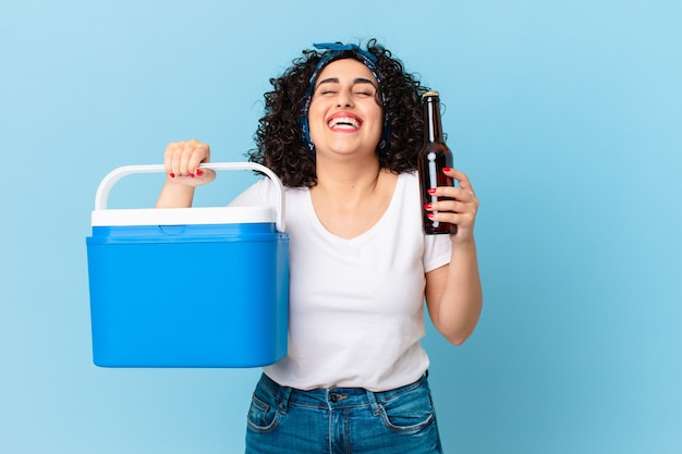 Pretty arab woman with a portable refrigerator and a beer