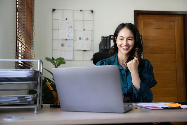 Pretty Asian businesswoman sitting on a laptop And the work came out successfully and the goal was achieved happy and satisfied with her