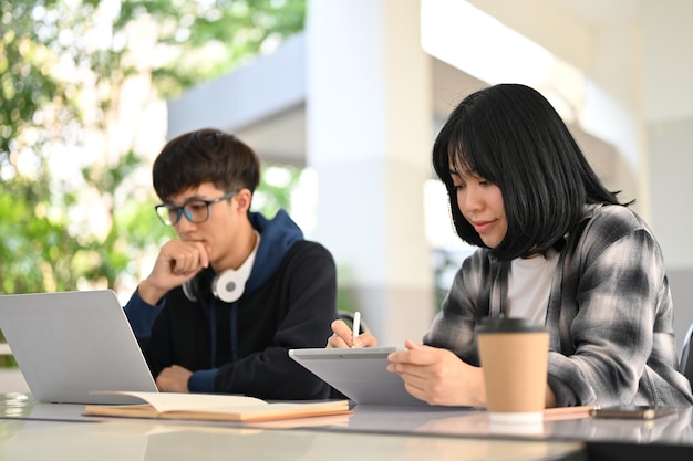 Pretty Asian female college student working on her schoolwork on her tablet