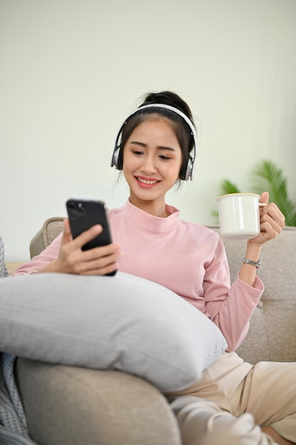 Pretty Asian girl chilling in her living room listening to music through headphones