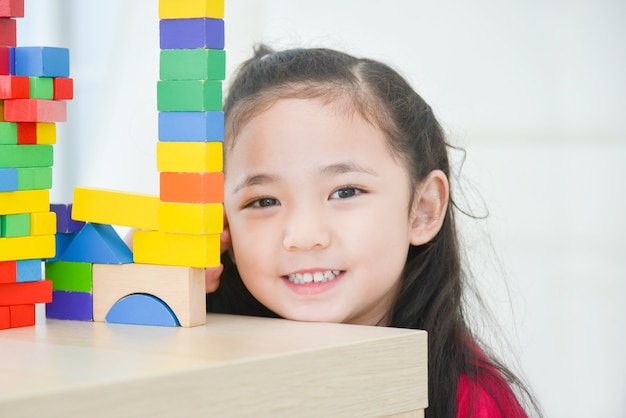 Pretty asian little girl playing with colorful wood blocks at home