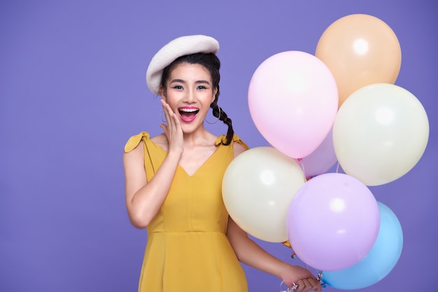 Pretty Asian woman at celebration party holding colorful balloon.