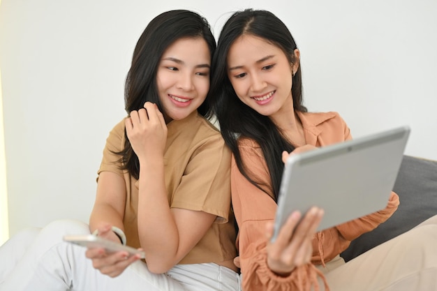 Pretty asian young women enjoy chatting and watching movie together in tablet