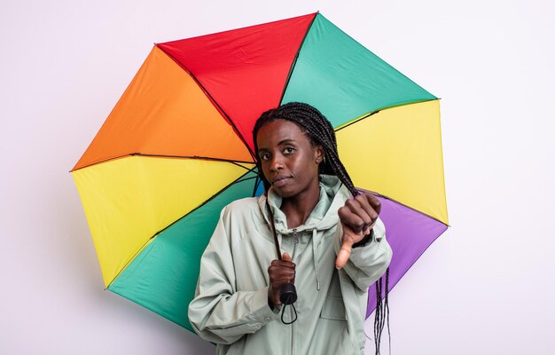 Pretty black woman feeling cross,showing thumbs down. umbrella concept