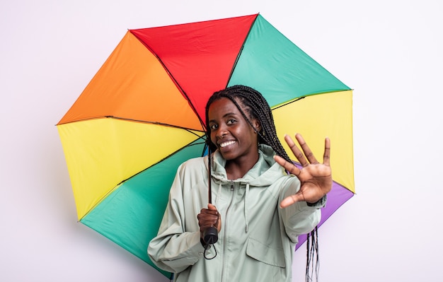 Pretty black woman smiling and looking friendly, showing number five. umbrella concept