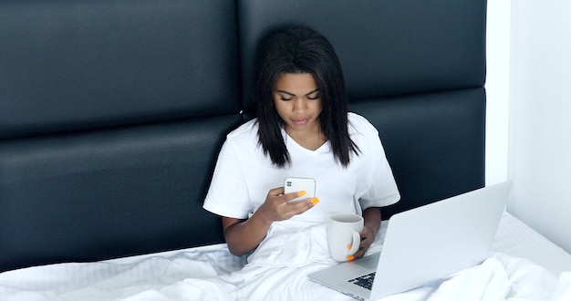 Pretty black woman using her laptop in bed.