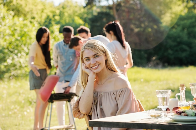 Pretty blond girl with toothy smile sitting on chair by served table