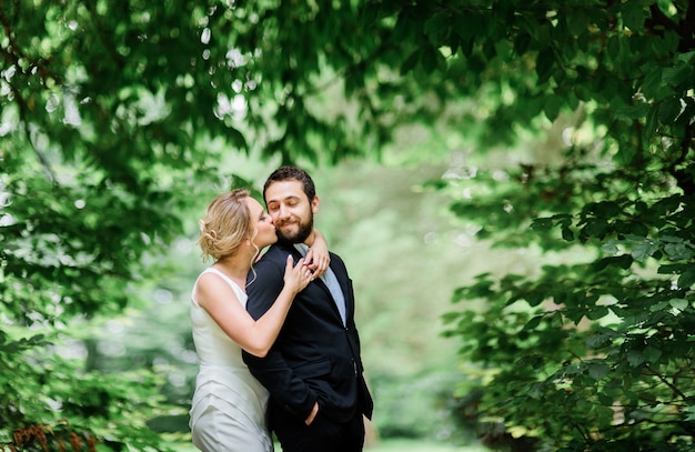 Pretty blonde bride hugs from behind happy bearded groom