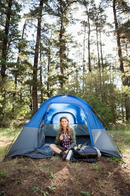 Pretty blonde camper smiling and sitting in tent