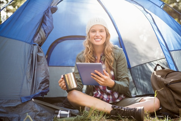 Pretty blonde camper using tablet and holding cup