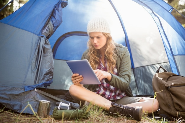 Pretty blonde camper using tablet and sitting in tent