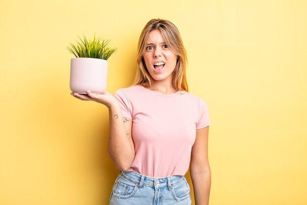 Pretty blonde girl feeling puzzled and confused. houseplant concept