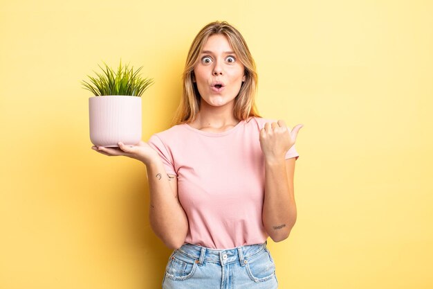 Pretty blonde girl looking astonished in disbelief. houseplant concept