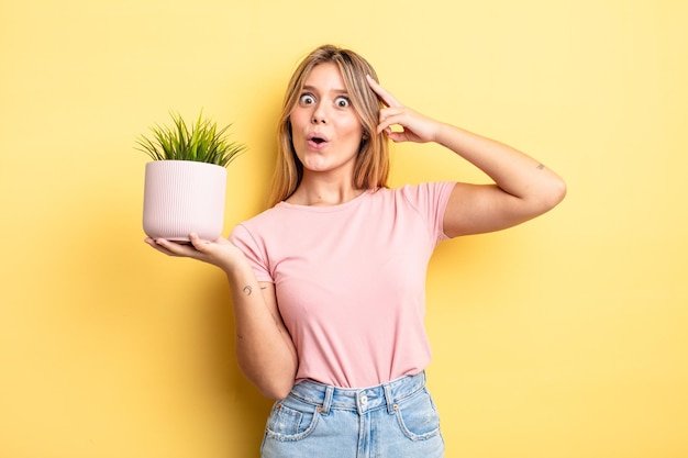 Pretty blonde girl looking happy, astonished and surprised. houseplant concept