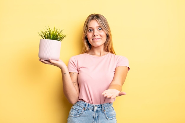 Pretty blonde girl smiling happily with friendly and  offering and showing a concept. houseplant concept