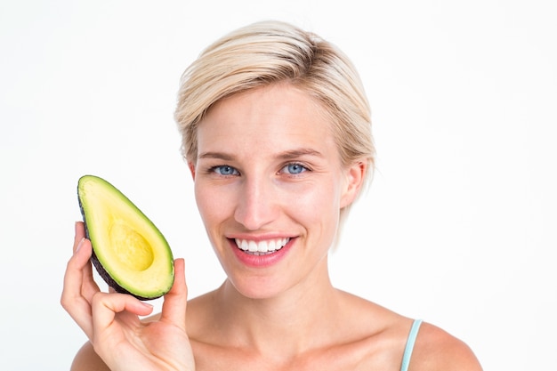 Pretty blonde holding half of an avocado 