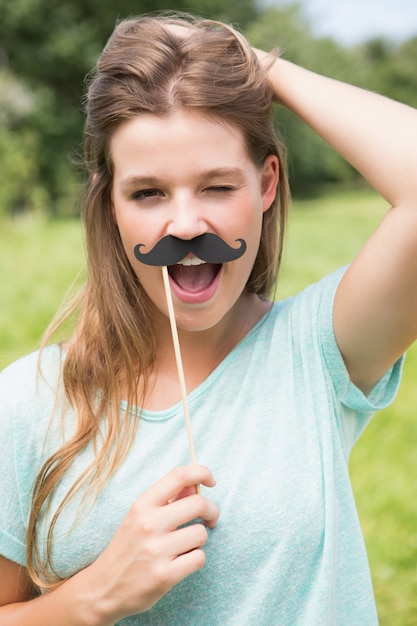 Pretty blonde smiling at camera with fake mustache 