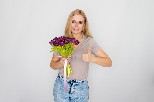 Pretty blonde woman holding purple tulips in her hands 