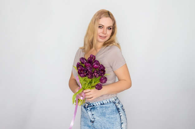 Pretty blonde woman holding purple tulips in her hands 