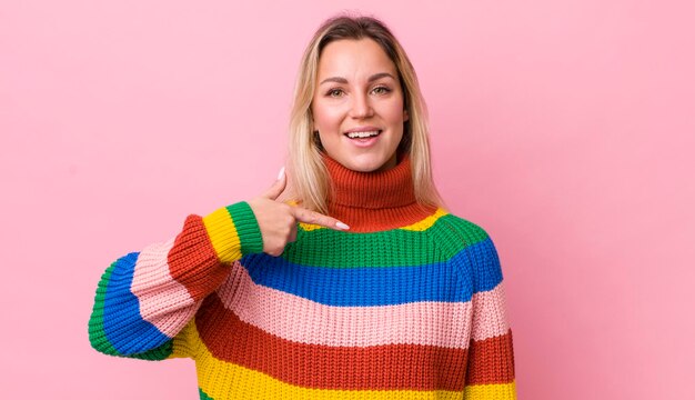 Photo pretty blonde woman looking happy proud and surprised cheerfully pointing to self feeling confident and lofty