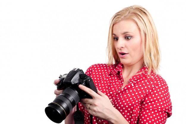 Pretty blonde woman photographer with her camera, on white