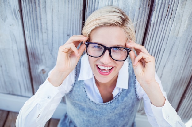 Pretty blonde woman smiling at the camera on wooden background