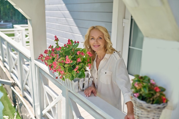 Pretty blonde woman in white with the flowers at her house